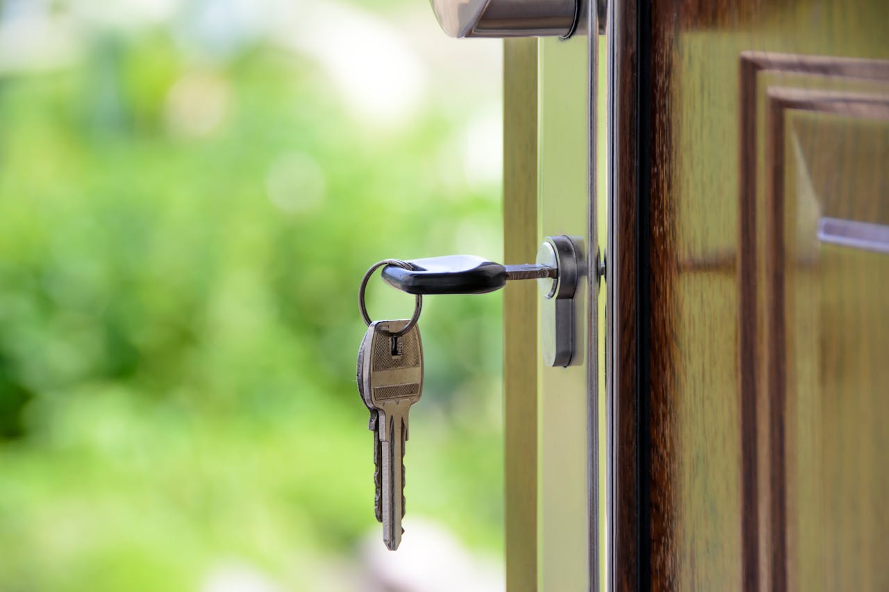 services-01 Key inserted in door lock against a blurred green background, symbolizing security and real estate.